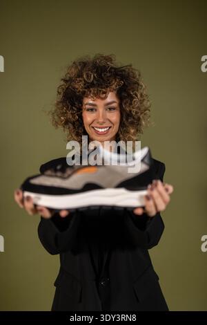 Eine Frau posiert und hält ein Paar Turnschuhe in der Hand Stockfoto