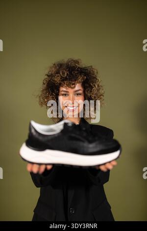 Eine Frau posiert und hält ein Paar Turnschuhe in der Hand Stockfoto