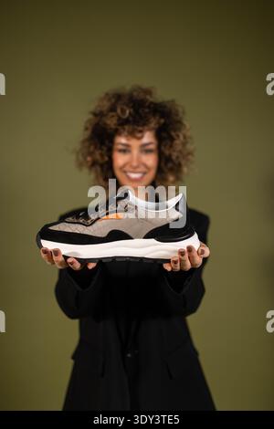 Eine Frau posiert und hält ein Paar Turnschuhe in der Hand Stockfoto