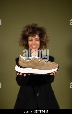 Eine Frau posiert und hält ein Paar Turnschuhe in der Hand Stockfoto