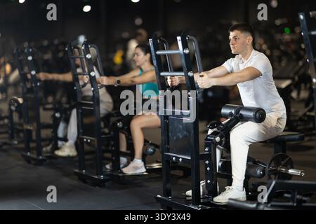 Ein Typ, der im Fitnessstudio auf dem Gerät sitzende Widerstandsübungen durchführt Stockfoto