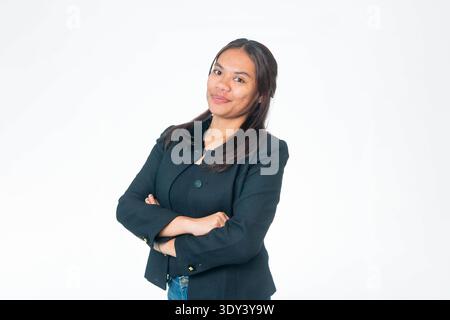 Porträt einer lächelnden indonesischen Frau, die eine schwarze strukturierte Jacke und eine blaue Jeans trägt, mit freundlichem Ausdruck in die Kamera blickt, isoliert auf weißem Rücken Stockfoto