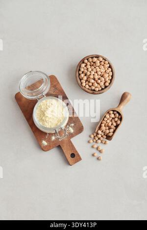 Kichererbsenmehl im Glas mit rohen Kichererbsen auf hellem Hintergrund, Draufsicht Stockfoto