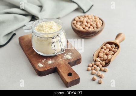 Kichererbsenmehl im Glas mit rohen Kichererbsen auf hellem Hintergrund, Nahaufnahme Stockfoto