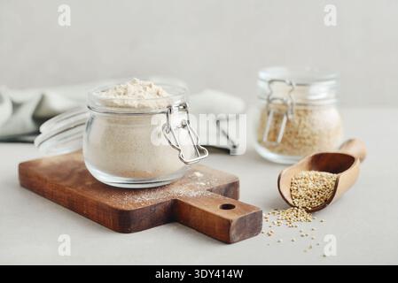 Amaranth Mehl im Glas mit roher Amaranth auf hellem Hintergrund, Nahaufnahme Stockfoto