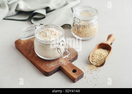 Amaranth Mehl im Glas mit roher Amaranth auf hellem Hintergrund, Nahaufnahme Stockfoto