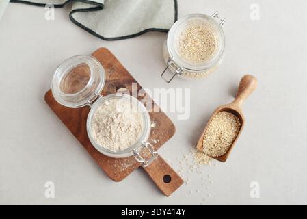 Amaranth Mehl in Glasgefäß mit roher Amaranth auf hellem Hintergrund, Draufsicht Stockfoto