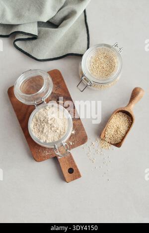 Amaranth Mehl in Glasgefäß mit roher Amaranth auf hellem Hintergrund, Draufsicht Stockfoto