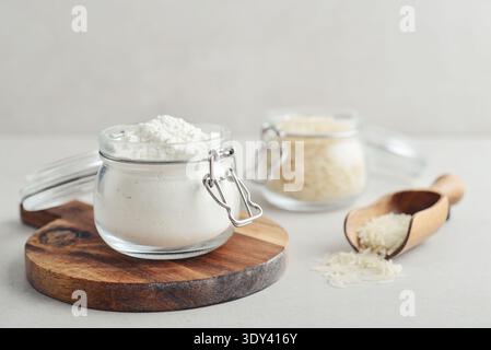 Reismehl im Glas mit roher Amaranth auf hellem Hintergrund, Nahaufnahme Stockfoto