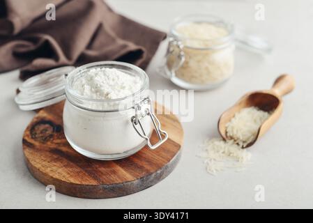 Reismehl im Glas mit roher Amaranth auf hellem Hintergrund, Nahaufnahme Stockfoto