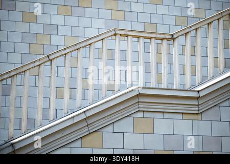 Außentreppe des Gebäudes mit geometrischem Geländer gegen eine gekachelte Wand Stockfoto