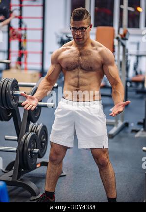 Starker Sportler, der nach einem intensiven Workout seine Muskeln in einem Fitnessstudio spannt und in russlands Fitnessszene Engagement und Kraft zum Ausdruck bringt Stockfoto