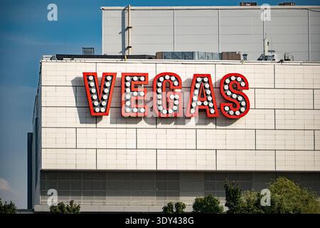 Großes Retro-Vegas-Schild mit roten Buchstaben und weißen Glühbirnen an einer Gebäudefassade Stockfoto