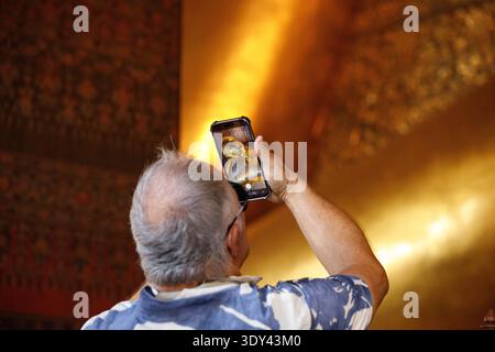 Senior man fotografiert den liegenden Buddha im Tempel, digitalen Lebensstil und Reisefotografie, Nahaufnahme, im Wat Pho. Stockfoto