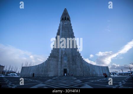 Die symmetrische Fassade der ikonischen Kirche Hallgrímskirkja in Reykjavik, Island, steht an einem sonnigen Wintertag hoch unter einem hellblauen Himmel. Stockfoto