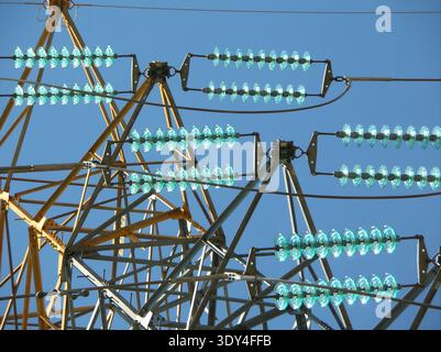 Nahaufnahme von türkisfarbenen Glasscheibenisolatoren an elektrischen Pylonquerarmen Stockfoto