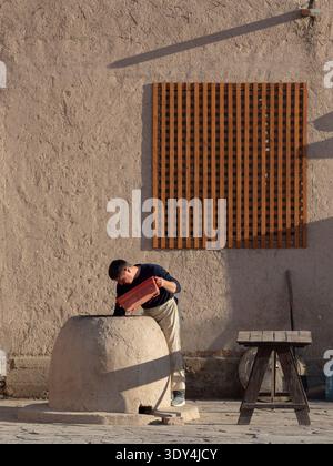 Baker bereitet traditionelles Brot im Tandoor-Tonofen am frühen Morgen in der Itchan Kala-Festung in Chiwa, Usbekistan zu. Alte Brotbacktradition Stockfoto