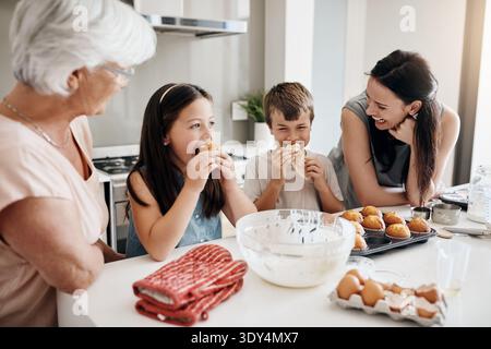 Oma, Mutter und Kinder mit Muffins in der Küche zum Geschmackstest, Liebe und Backen zu Hause. Leute, Frauen und Kinder mit Snack, Essen Stockfoto