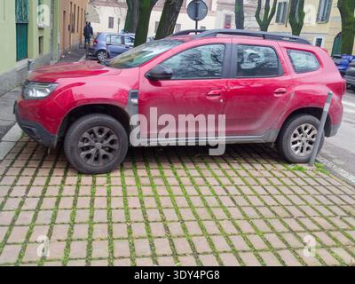 Cremona, Italien - 2. Februar 2026 Ein roter Dacia Duster SUV steht auf einem Gitter aus Betonfertigern mit Gras in den Lücken, was auf eine Öko-fri hindeutet Stockfoto