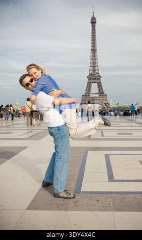 Glückliches junges Paar auf dem Hintergrund des Eiffelturms in Paris. Flitterwochen in Europa Stockfoto