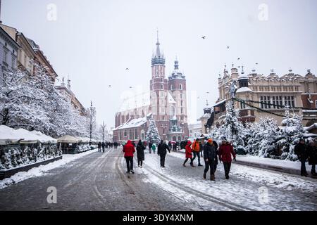 St. Marienkirche und das Sukiennice-Leinenhaus, die in einem Schneesturm auf dem schneebedeckten Hauptmarkt in Krakau, Polen, im Winter eingehüllt sind Stockfoto
