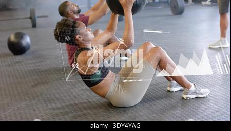 Frauen mit Sport-BH und Shorts, die im Fitnessstudio einen Medizinball mit AR-Überzug halten Stockfoto