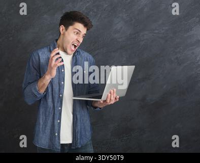Junger ernster Mann, der Laptop benutzt Stockfoto