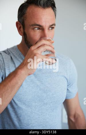 Mensch, Trinkwasser und Denken zu Hause mit Durst, Reflexion und Durchbruch mit Hydratation am Morgen. Reife Person, Glas und Flüssigkeit für Entgiftung, Darm Stockfoto
