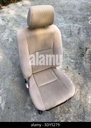 Gebrauchter beigefarbener Autositz mit entfernter Kopfstütze zur Reparatur oder zum Austausch. Stockfoto
