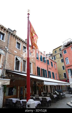 Stimmungsvolle nächtliche Straßenszene in Venedig mit beleuchteten Schaufensterfronten, historischen Gebäuden und Menschen, die durch einen ruhigen Platz spazieren. Stockfoto