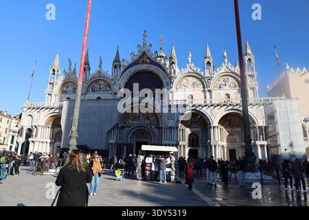 Nahaufnahme der Markusbasilika mit kunstvollen Bögen, Mosaiken und bildhauerischen Details unter einem klaren Himmel. Stockfoto