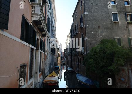 Schmaler Wohnkanal, gesäumt von historischen Gebäuden, festgemachte Boote und ruhiges Wasser, gesehen von einer Brücke in Venedig. Stockfoto
