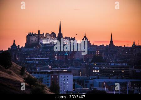 Skyline von Edinburgh City bei Dämmerung von Arthur's Seat mit Silhouette der Royal Mile und beleuchtetem Edinburgh Castle vor dem Orange Sunset Sky, Schottland Stockfoto