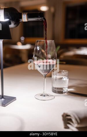 Rotwein in Kristallglas im Speisesaal der Dolomiten gegossen Stockfoto