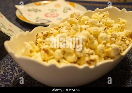 Popcorn in einer Schüssel auf einer blauen Tischdecke. Foto aus Anlass eines Wachses zu Hause unter Freunden Stockfoto