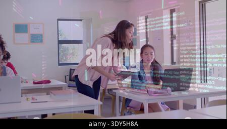 Lehnender Kursleiter in rosa Top-Tablett auf Schüler-Laptop in der Schulklasse mit Code-Overlay Stockfoto