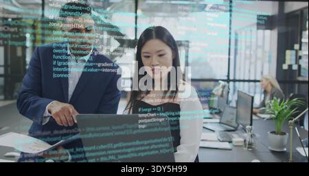 Zeigender Mann im dunklen Anzug, der Frau in Bluse am Laptop führt, offenes Büro mit Code-Reflexionen Stockfoto