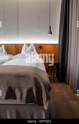 Boutique-Hotelzimmer in den Dolomiten mit Doppelbett und Lampe Stockfoto