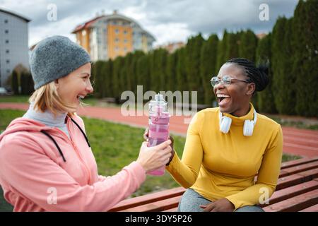 Verschiedene Freunde lachen und teilen sich Wasser auf der Sportstrecke Stockfoto