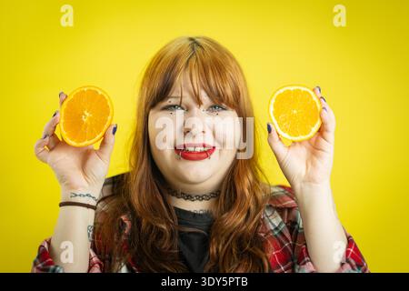 Eine junge Frau, die frische Orangenhälften hält und lächelt Stockfoto