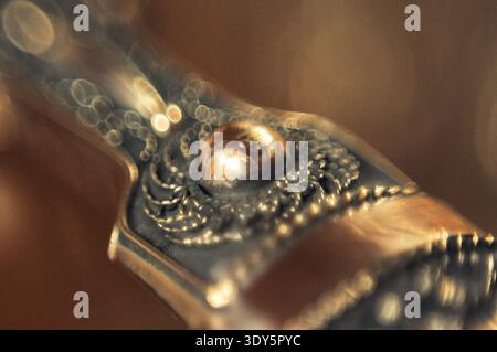 Dieses detailreiche Makrofoto erfasst die exquisite Handwerkskunst eines antiken Metallartefakts und hebt seine strukturierte Oberfläche und dekorative Optik hervor Stockfoto