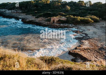 Wellen brechen am Cala BRAFi Beach mit Stone Hut, Mallorca Stockfoto
