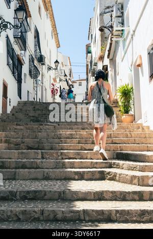 Frau, die eine Steintreppe in der weißen mediterranen Stadt hochgeht Stockfoto