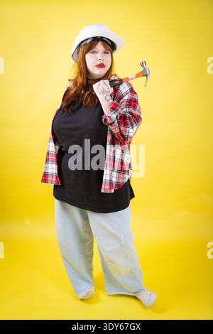 Eine junge Frau mit Hammer und Schutzhelm Stockfoto