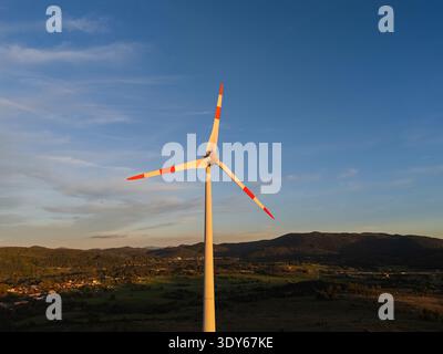Windturbinen stehen während des Sonnenuntergangs auf Hügeln und zeigen die Nutzung erneuerbarer Energien und die Erzeugung sauberer Energie in der Landschaft. Stockfoto