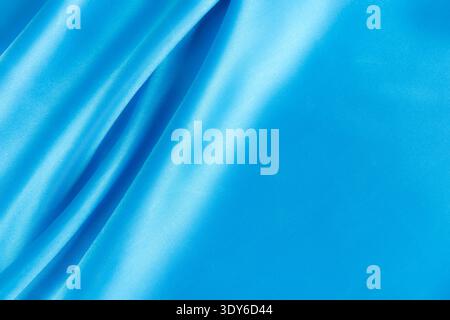 Blauer Seidensatin-Stoff mit Wellenmuster und glatter Textur Stockfoto