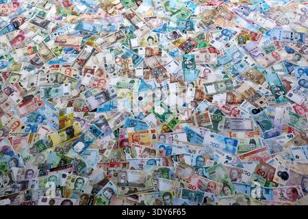 Viele Banknoten unterschiedlicher Währung. Eine große Menge von zufälligen Geldrechnungen aus der Nähe. Währungsumtausch-Konzept Stockfoto