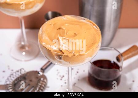 Dalgona Espresso-Martini-Cocktail mit Schlagsahne und cremigem Likör, viraler Sommercocktail in zwei Martini-Gläsern, mit Shaker und Bar-ut Stockfoto