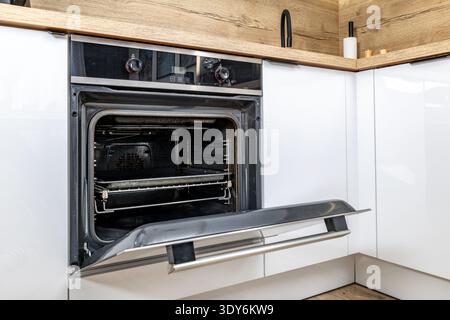 Offene Ofentür, moderne Küchenmöbel mit weißen Fronten, eingebauter Backofen, Backofen-Installation, Küchenrenovierung Stockfoto