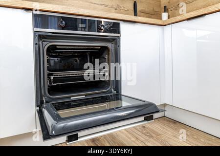 Offene Ofentür, moderne Küchenmöbel mit weißen Fronten, eingebauter Backofen, Backofen-Installation, Küchenrenovierung Stockfoto